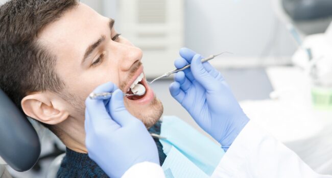 Young man visiting dentist at the clinic Close up shot of a young bearded man having his teeth examined by a professional dentist health medicine clinic profession medical industry vitality consciousness dental oral clinical concept